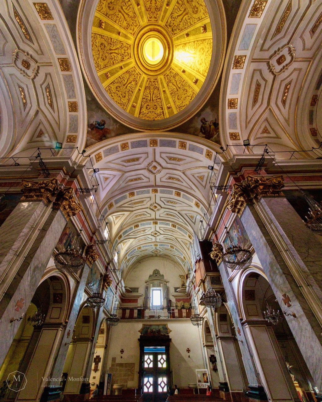 Nave de la iglesia de Santa Mónica en contrapicado, con la cúpula dorada iluminada sobre las bóvedas decoradas