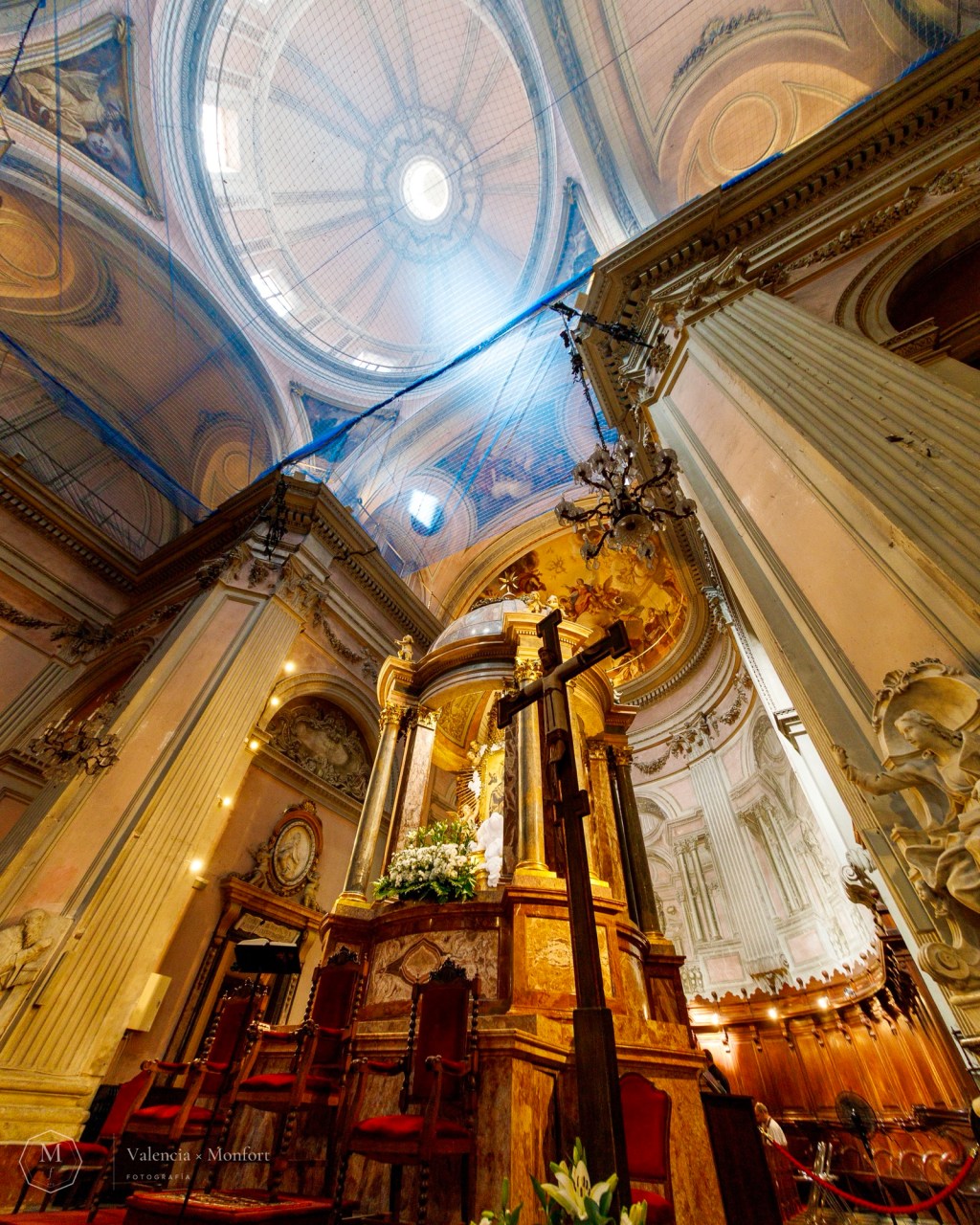 Crucifijo y altar de una iglesia en contrapicado, con la cúpula iluminada al fondo