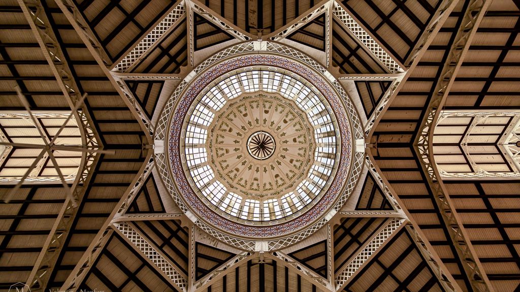 Cúpula del Mercado Central de Valencia vista desde abajo, con la estructura de hierro formando una estrella alrededor de la vidriera